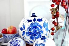 16 white pumpkins painted with blue and navy blooms inspired by chinoiserie are adorable for vintage fall decor