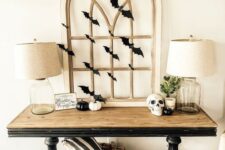 23 a stylish rustic vintage console table with black and white pumpkins, a skull, a vintage window frame and black paper bats covering it