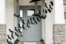 25 a whimsy Halloween porch with witches’ legs and umbrellas, orange pumpkins, candle lanterns and bats