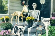 26 a funny Halloween porch scene with a skeleton and a skeleton unicorn, pumpkins, candle lanterns, buntings and black spider web