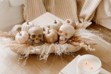 a neutral Halloween arrangement of pampas grass, white pumpkins, skulls is a great decor idea for thhis holiday