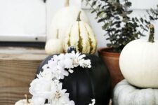 28 a black pumpkin decorated with gorgeous and lush white blooms forming a crescent moon looks amazing for Halloween
