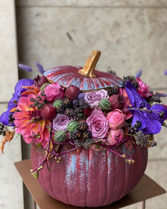 A jaw dropping purple Halloween pumpkin with pink, mauve and violet blooms, berries and cherries is a chic idea