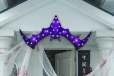 38 a bold and pretty purple bat marquee light over the entrace instead of a wreath or another Halloween door decoration