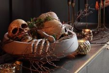 46 refined Halloween decor with a bowl filled with skeleton hands, skulls and moss, branches, candles around is amazing