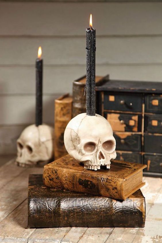 stacked vintage books with skulls as candleholders look very chic, nice and bold and make the space feel like Halloween