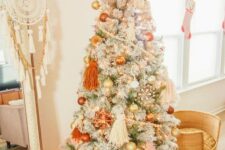 02 a lovely flocked Christmas tree with pastel boho decor, orange, gold and blush ornaments, beadsm large tassels and lights