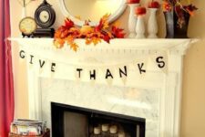 08 a bright rustic Thanksgiving mantel with bold leaf arrangements, pumpkins on stands, some banners and candles in candleholders