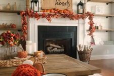 10 a cozy rustic Thanksgiving mantel with a bold leaf garland, orange pumpkins, a paper hanging and candle lanterns