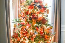 12 a gorgeous bright Thanksgiving tree with lights, ornage, gold and black ornaments, faux leaves, foliage and a pumpkin on top