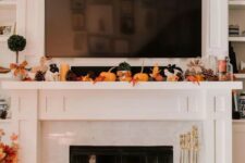 14 a lovely Thanksgiving mantel with bold leaves, candles, pinecones, small pumpkins on the mantel and larger ones next to the fireplace