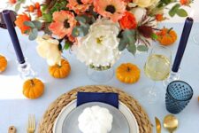 18 a bold and contrasting orange and navy Thanksgiving place setting with a navy napkin and candles, orange pumpkins and blooms
