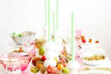 20 a bold Thanksgiving tablescape with pink glasses, green candles, bold fruit and candles on the table and some pinecones