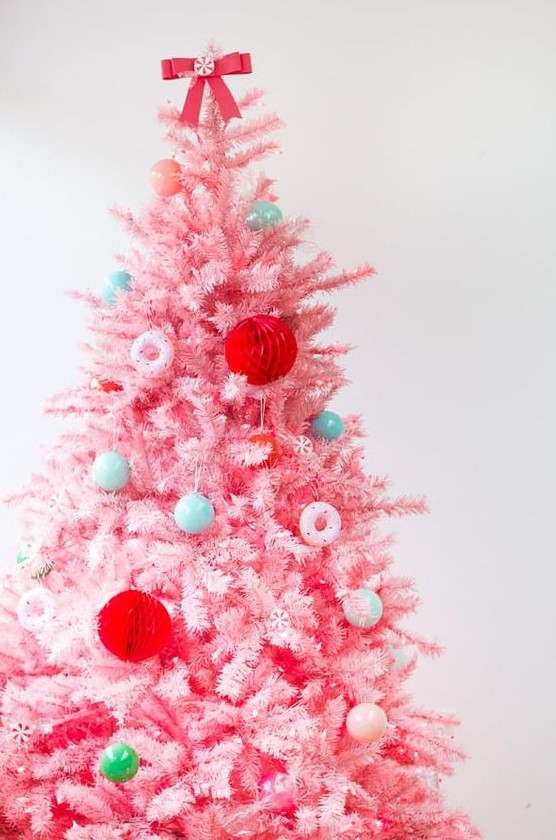 A pink Christmas tree with mini blue and green ornaments, with red paper balls and pink donut ornaments is a fun candy inspired decor idea