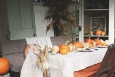 23 a bright fall tablescape with a white and an orange tablecloth, pumpkins, corn cobs and plates and placemats