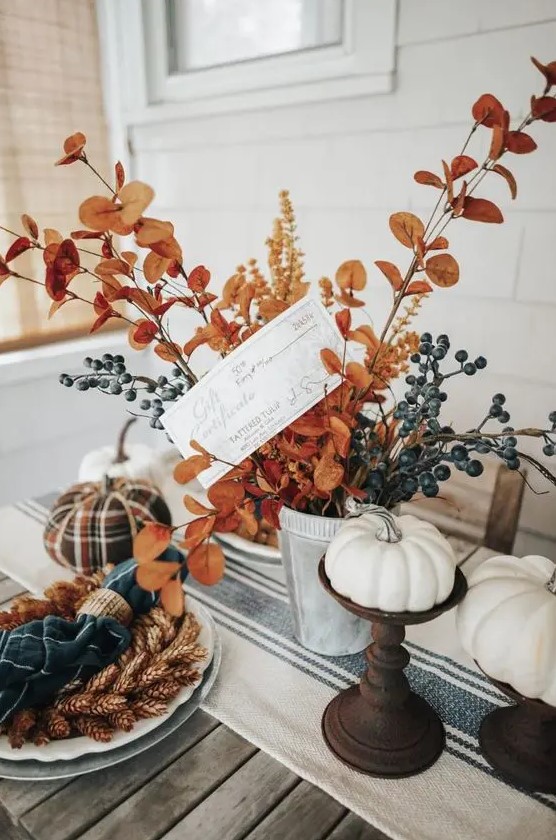 a bright Thanksgiving table with a striped runner, wheat, pinecones, leaves and pumpkins - faux and real ones plus blue napkins