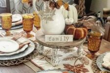 28 a cozy rustic Thanksgiving tablescape with an embroidered table runner and rust plaid napkins, a stand with faux pumpkins, leaves and pinecones