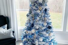31 an icy blue Christmas tree decorated with pale and navy ornaments, white, gold and silver ones plus frosted branches with pompoms on its top is a creative idea