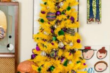 32 a yellow Christmas tree styled with green, silver and purple ornaments looks super fun, bold and chic