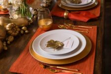 33 a refined Thanskgiving tablescape with terracotta placemats and napkins, gilded chargers, glasses, cutlery and veggies on the table