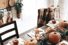 35 a simple rustic Thanksgiving table with a lush greenery runner, rust pumpkins and gourds, copper teapots and mugs
