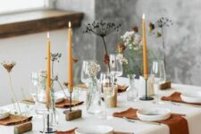 38 a stylish modern meets boho Thanksgiving tablescape with rust napkins and candles, fresh and dried blooms, white plates and wooden stands