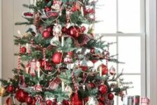 43 a vintage-inspired Christmas tree with red ornaments, lights and candy candes looks bold and catchy