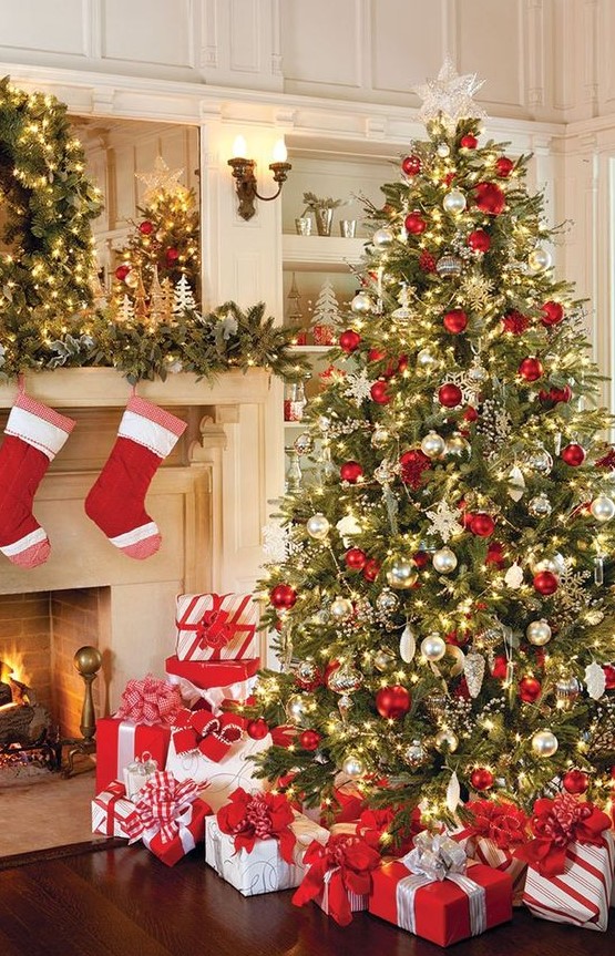 a large Christmas tree with red, gold and mother of pearl ornaments, lights and lots of red and white gift boxes