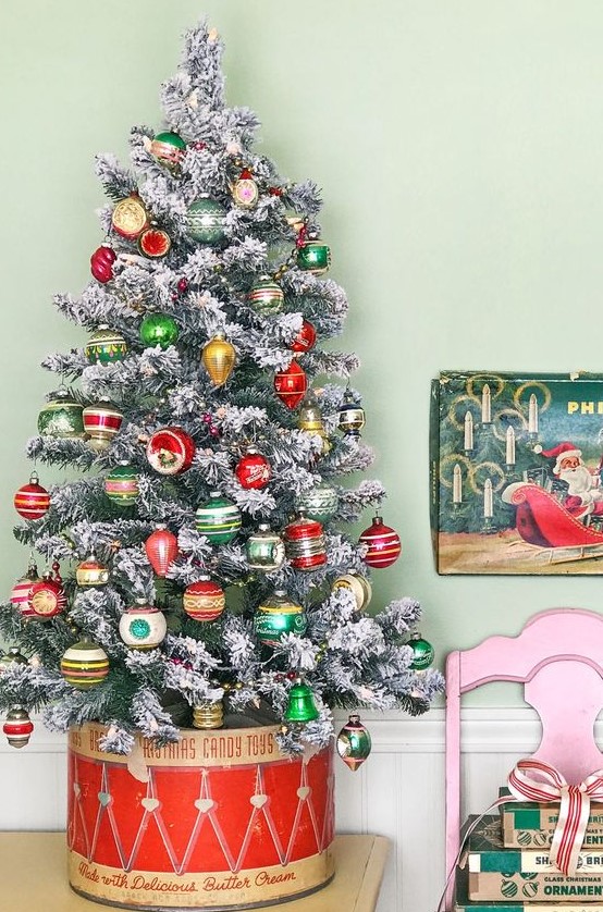 a flocked Christmas tree decorated with colorful vintage Christmas ornaments placed into a drum is a creative idea