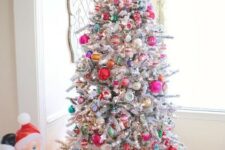 67 a flocked Christmas tree decorated with red, pink, green, yellow and silver ornaments of various sizes and shapes and spruced up with lights