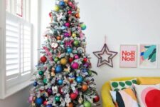 69 a flocked Christmas tree decorated with super colorful ornaments and rainbows is a gorgeous idea for a bold space
