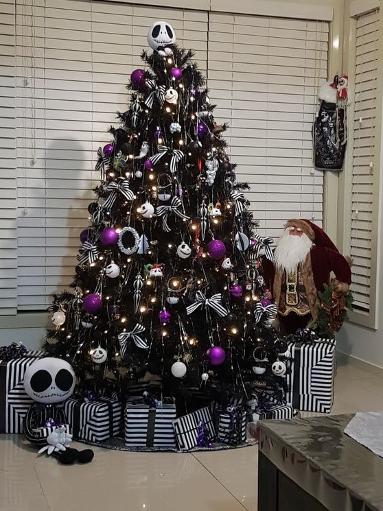 a Nightmare Before Christmas tree in black, with white and purple ornaments, striped bows and wreaths and Jack Skellington decor