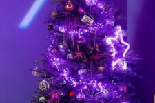a bright purple Christmas tree decorated with purple lights and a neon star, black, silver and red ornaments is a bold idea
