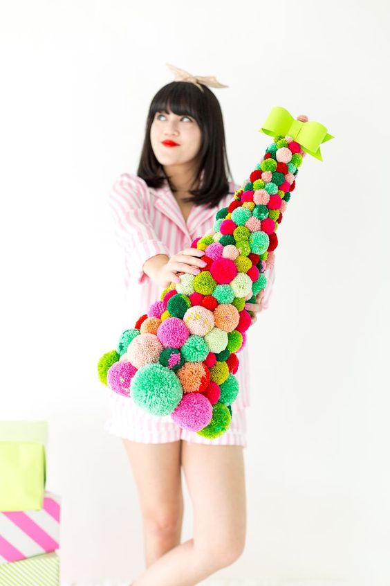 A colorful pompom cone shaped Christmas tree topped with a bold bow is an amazing idea for bright holiday decor