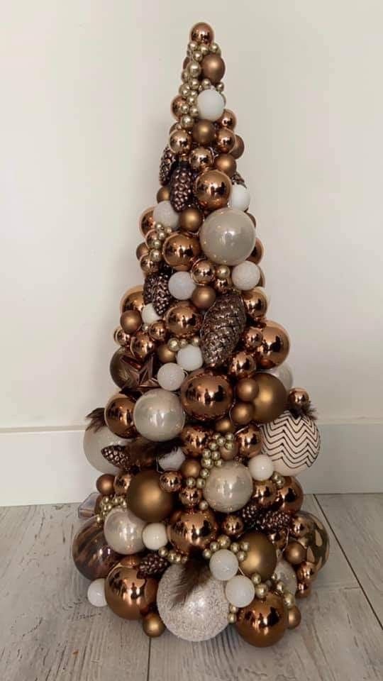 A cone shaped Christmas tree completely covered with brown, beige, pear and white ornaments of various shapes