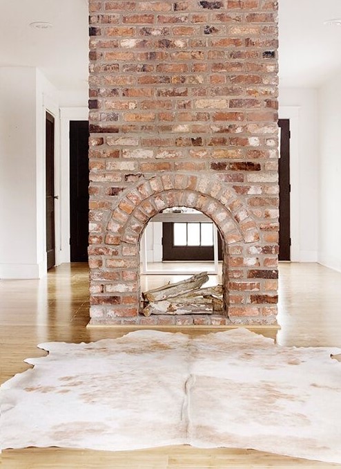 A gorgeous double sided fireplace clad with brick looks very vintage and brings a character and a story to the room