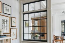 a large French window with black framing connects the living room and the entryway and lets more natural light inside