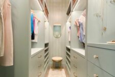 a mint green narrow closet with lots of drawers and open storage compartments, with lit up shelves and a chandelier