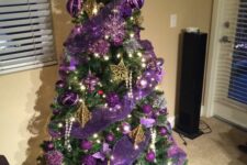 a shiny Christmas tree with purple ribbons and ornaments, gold stars and large ribbon bows plus lights is a cool idea