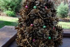 a small pinecone Christmas tree decorated with colorful beads is a cute rustic decoration