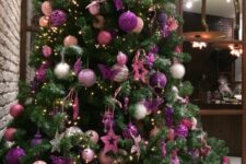 a stylish Christmas tree decorated with light pink, silver and purple ornaments and stars and with lights