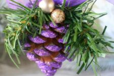 dip pinecones in purple glitter for a fun and bright look, when paired with gold balls this is a bright ornament to hang in your home