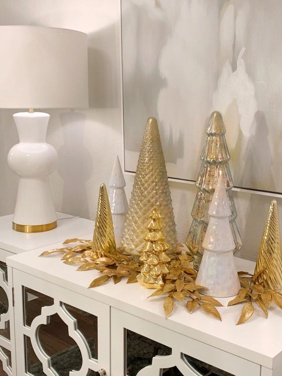 White, silver and gold cone shaped Christmas trees and gilded leaves are great for styling a console or a mantel