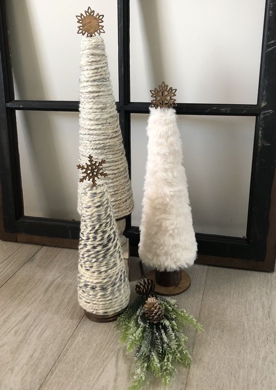 Yarn and faux fur cone shaped Christmas trees topped with wodoen snowflakes will be a nice idea for a rustic space