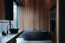 02 a Japandi bathroom with black and light-colored wood is highlighted with a natural stone slab and countertop