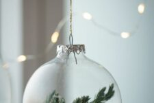 06 a clear glass Christmas ornament with faux snow and evergreens is a dreamy winter-inspired decor idea