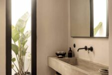 07 a concrete Japandi bathroom with a large mirror, a built-in concrete vanity and a shelf, a vertical window plus a black stool
