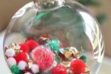 11 a clear glass Christmas ornament with white, red, green pompoms and gold bells is a cool decor idea done in the traditional colors