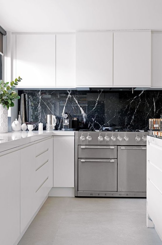 A black marble kitchen backsplash is a very luxurious touch to these ultra minimalist white cabinets