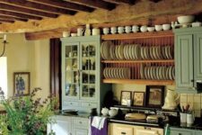 15 a lovely vintage kitchen with blue cabinets, a vintage hearth, open shelves for plates, wooden beams and a wooden dining set